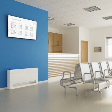 Stelrad white low surface temperature radiator against a blue wall in a doctor's waiting room