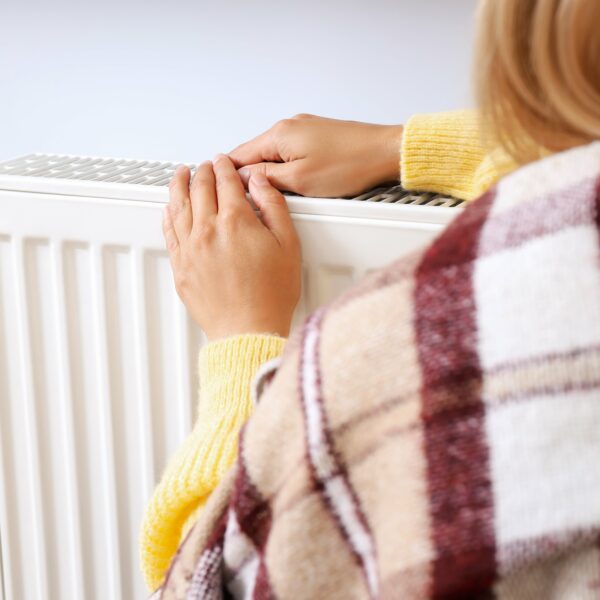 woman warming her hands on a radiator