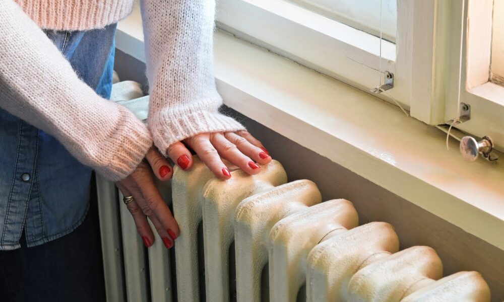A woman checking the temperature of a radiator by touching it