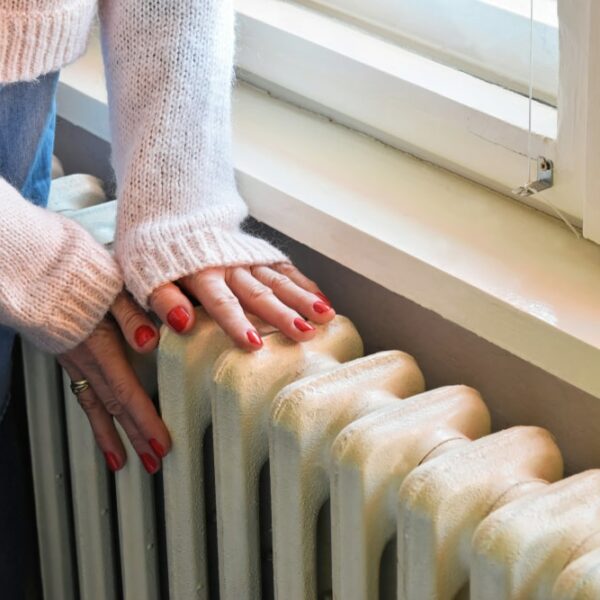 A woman checking the temperature of a radiator by touching it