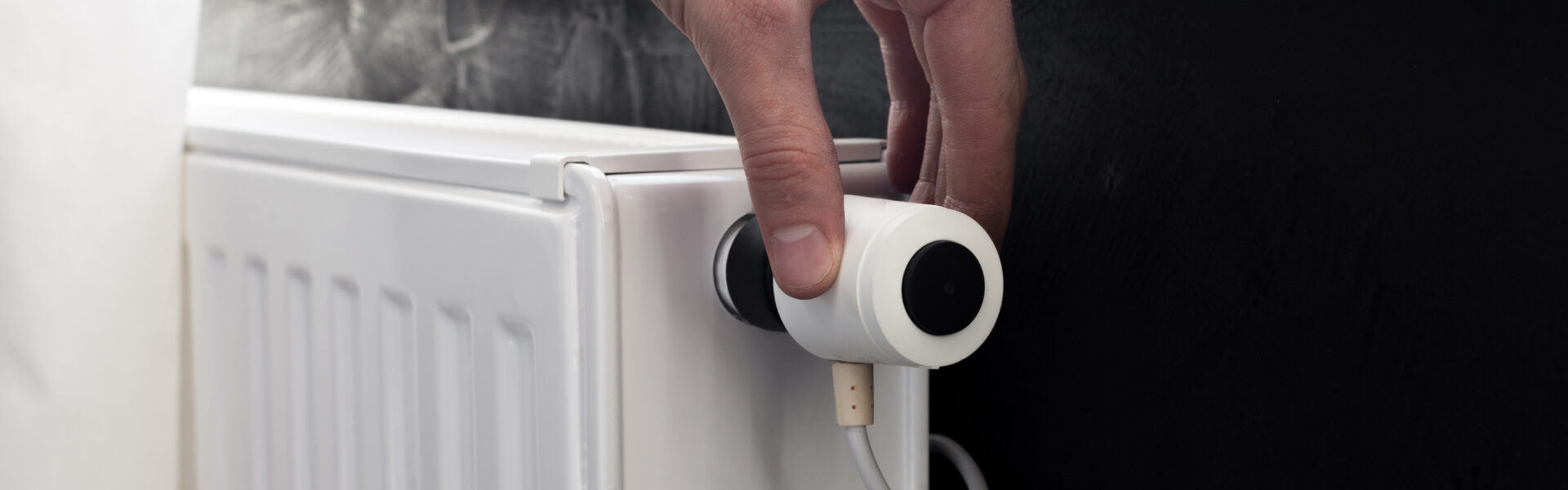 A hand adjusting the temperature on an electric radiator