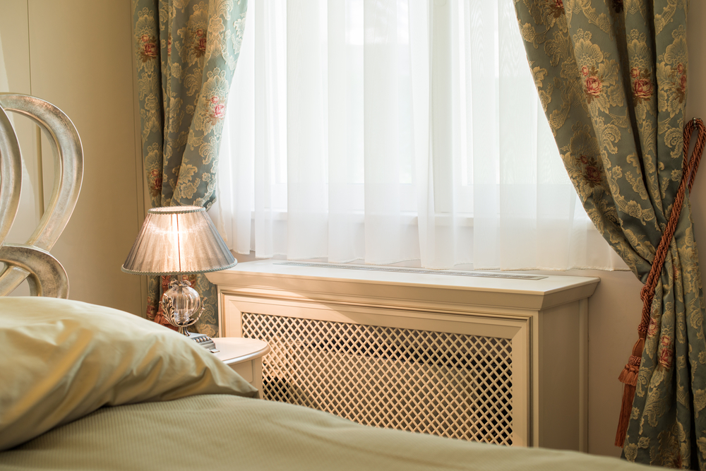 A radiator with a wooden cover in a bedroom